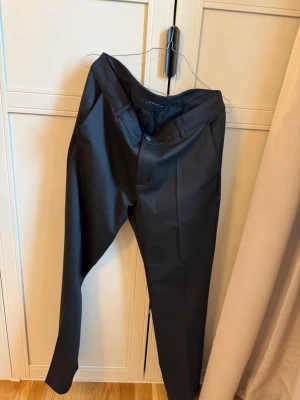 Svart kostymbyxor med pressveck från LC Waikiki - Snygga svarta kostymbyxor med raka ben och klassiskt pressveck. Byxorna har sidfickor och bälteshällor i midjan. Perfekta för en stilren och clean look. Materialet ser ut att vara en blandning av polyester och viskos för en mjuk känsla.
