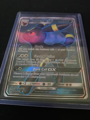 Umbreon GX holografiskt Pokémonkort - Umbreon GX holografiskt Pokémonkort med snygg svart, blå och gul design. Kortet har coola attacker som Shadow Bullet och Dark Call GX. Levereras i genomskinligt plastfodral, perfekt för samlare och Pokémonentusiaster.