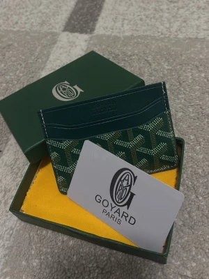 Goy4ard plånbok grön - Snyggt och stilrent kortfodral från Goy4ard i grått med klassiskt mönster och logotyp. Fodralet är tillverkat i läder och har flera fack för kort. Kommer med original ask och tygpåse. Perfekt för dig som vill ha något exklusivt och trendigt.