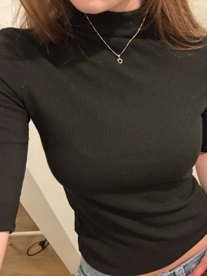 Svart ribbad topp med halv polo - Svart topp med trekvartsärm och polo från mango.