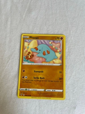 Phanpy Pokémonkort 2022 - Phanpy Pokémonkort från 2022 med gul ram och färgglad illustration. Kortet har attackerna Stampede och Strike Back. Perfekt för samlare eller Pokémonfans som vill utöka sin kortsamling.