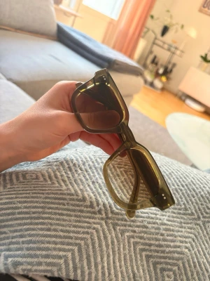 Gröna fyrkantiga solglasögon - Snygga solglasögon med transparent grönt båge och fyrkantig form. Glasen är mörka och bågarna har små silvriga detaljer vid hörnen. Perfekta för att lyfta din stil under soliga dagar.