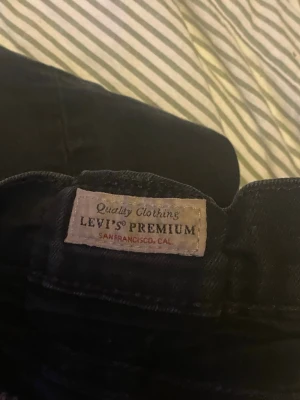 Svarta Levi's Premium jeans - Säljer ett par svarta Levi's Premium jeans med klassisk femficksdesign och raka ben. Jeansen har knappstängning och är tillverkade i ett slitstarkt denim-material. Perfekta för dig som gillar tidlös stil och kvalitet.