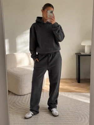 Mörkgrå hoodie och mjukisbyxor set - Säljer ett mörkgrått loungewear-set med hoodie och matchande mjukisbyxor. Hoodien har en stor huva och ribbade muddar, byxorna har dragsko i midjan och sidofickor. Perfekt för chill dagar hemma eller när du vill vara bekväm.