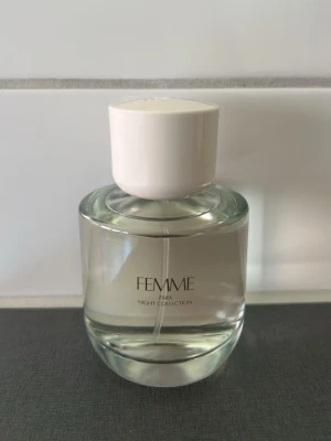 FEMME parfym från Zara Night Collection - Elegant parfymflaska från Zara Night Collection med namnet FEMME. Flaskan är rund och transparent med en vit, cylindrisk kork. Perfekt för dig som vill ha en stilren och modern doft på hyllan.