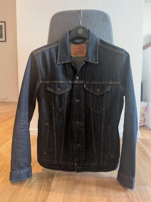 Mörkblå jeansjacka från Levi's - Säljer en klassisk mörkblå truckerjacka type III från Levi's i mycket fint skick. Inköpt i USA för några år sedan men väldigt lite använd. 