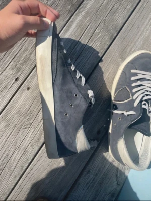 Philippe model  - Snygga mörkblå sneakers med vita snören och vit sula. Skorna har en låg profil och är tillverkade i mockaliknande material med vita detaljer vid häl och tå. Perfekta för en avslappnad och trendig stil.