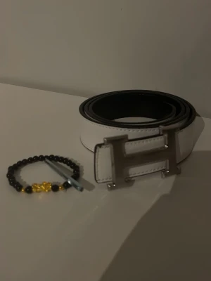 H&M bälte  - Helt ny H&M bälte storlek 125 ingår me verktyg som man kan göra egna hål med och en stilig armband, man kan använda Båda sidorna på bältet svart och vitt så de är 2 in 1 