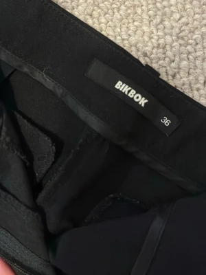 Svarta kostymbyxor från BikBok - Snygga svarta kostymbyxor från BikBok i klassisk rak modell. Byxorna har en stilren look och passar perfekt till en dressad outfit. Tillverkade i ett mjukt och följsamt material som ger en bekväm känsla hela dagen.