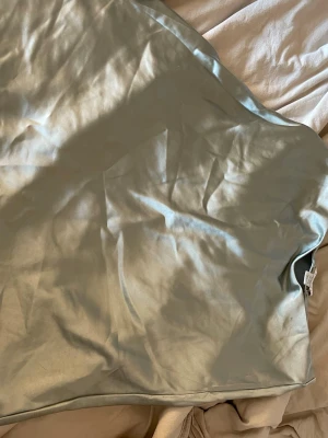 Ljusgrön satin kjol från Amisu - Säljer en ljusgrön kjol från Amisu i mjukt satinliknande material. Kjolen har en enkel och stilren design med lätt glansig yta och rak passform.