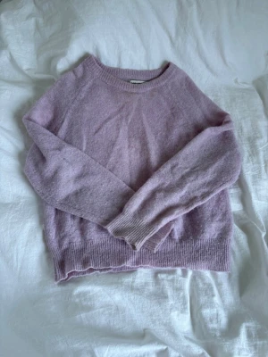 Ljusrosa stickad tröja - Mysig ljusrosa stickad tröja med rund halsringning och långa ärmar. Tröjan har ribbade muddar vid ärmslut och nederkant. Skönt ej stickigt material och tunn men varm tröja. Perfekt på en sommarkväll. Säljs pågrund av att den ej kommit eller kommer till användning. 
