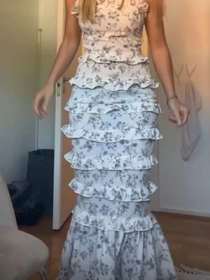 Vit blommig långklänning med volanger - !!!Bilderna är lånade förutom den första!!!Super fin balklänning som bara har används 1 gång, är i storlek 36 men passar mig som brukar har S💝💝