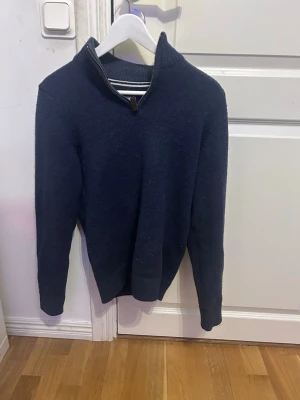 Mörkblå pier one. Stickad tröja, halfzip  - Mörkblå stickad tröja med halv dragkedja i halsen och ribbade muddar. Tröjan har en klassisk passform och är perfekt för lager-på-lager. Materialet är  mjukt och värmande, perfekt för att ha under vinterjacka och gå runt i bara den i sommar/vår.