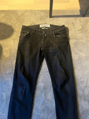 Svarta jeans från Jacob Cohen - Snygga svarta jeans från Jacob Cohen med klassisk femficksdesign och smal passform. Jeansen har diskreta sömmar och en stilren look, perfekta för dig som gillar en clean och modern stil.