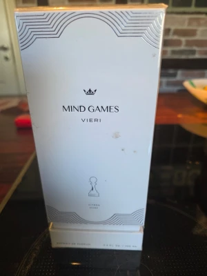 Mind Games Vieri parfym 100ml - Lyxig parfym från Mind Games i modellen Vieri. Flaskan är vit med eleganta svarta detaljer och har en stilren, modern design. Förpackningen har schackinspirerade motiv och rymmer 100 ml extrait de parfum.