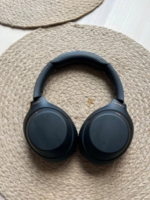 Sony WH-1000XM4 Wireless - Snygga svarta over-ear hörlurar från Sony med mjuka, vadderade öronkuddar och justerbart huvudband. Klassisk design i matt plast och konstläder som ger en bekväm känsla även vid längre lyssning. Perfekta för musik, gaming eller poddar.
