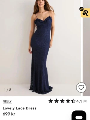 Marinblå spetsklänning från Nelly - Elegant långklänning i marinblå spets från Nelly. Klänningen har smala axelband, v-ringad urringning med volangdetalj och figurnära passform. Perfekt för speciella tillfällen där du vill känna dig extra fin.