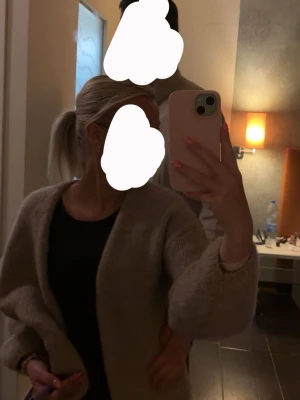 Beige fluffig kofta - Mysig beige kofta med lös passform och långa ärmar. Koftan har en fluffig textur och är öppen framtill utan knappar. Perfekt för lager-på-lager och chill vardagsstil.