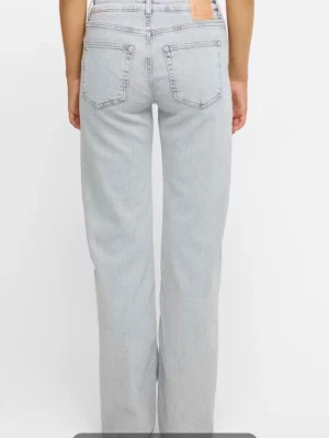 Ljusgråa raka jeans med hög midja - Snygga ljus gråa jeans med raka ben och hög midja. Klassisk femficksmodell med bälteshällor och knappgylf. Jeansen har en avslappnad passform och är tillverkade i denim. Perfekta för en trendig och avslappnad stil.