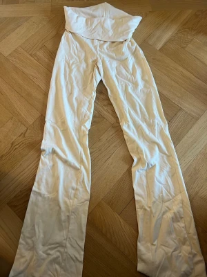 Vita leggings från Gina Tricot - Snygga vita leggings från Gina Tricot med hög midja och utsvängda ben. Tillverkade i mjukt och stretchigt material som sitter skönt på kroppen. Perfekta för en trendig och avslappnad look.