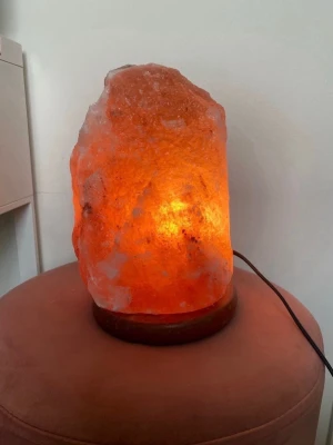 Orange saltlampa i kristall - Unik orange saltlampa i kristall med naturlig, ojämn form och träfot. Lampan ger ett mysigt sken när den är tänd och har en sladd för elanslutning! Väger 7kg☺️endast upphämtning i Göteborg då den är för stor för att frakta! Fick i present för ett tag sedan så vet ej vart den är ifrån!🫶🏼
