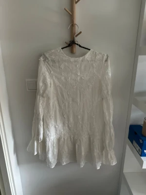 Vit klänning med volang och knyt i rygg!🤍 - Superfin vit klänning med broderade blommor med lång ärm och volang nertill. klänningen har rund halsringning fram och en djupare öppning bak med knytband. Perfekt för dig som gillar fina detaljer och en luftig känsla.🌼🤍 den är ifrån NA-KD i storlek 32! väldigt fint skick🌼