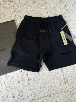 Essentials shorts - Svart - Svarta shorts från Essentials med elastisk midja och snörning. Riktigt sköna nu inför sommaren och passar med allt. Storlek S original tags och påse medföljer. Pris kan alltid diskuteras vid snabb affär.
