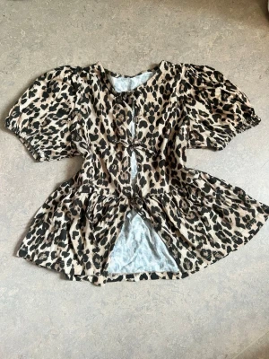Leopardmönstrad blus med puffärm - Snygg blus med leopardmönster och puffiga korta ärmar. Blusen har en markerad midja och volang nedtill som ger en trendig siluett. Perfekt för dig som vill sticka ut med ett djurmönster. Ingen synlig logga eller märke.