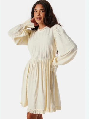 Viscose Frill Dress - Supersöt ljusgul klänning med volangdetaljer vid ärmslut och nederkant. Klänningen har långärmade puffärmar, rund halsringning och lätt rynkad midja för en feminin siluett. Tillverkad i mjukt viskos som känns luftigt och bekvämt. Passar S och M! 