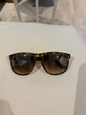 Ray-Ban Boyfriend solglasögon leopard - Snygga Ray-Ban Boyfriends solglasögon med leopardmönstrad båge i bruna och gula toner. Klassisk form med mörka, tonade glas. Perfekta för dig som vill ha en tidlös och trendig accessoar till sommaren.
