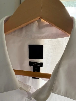 Vit slim fit skjorta L - Klassisk vit skjorta i slim fit-modell med lång ärm och knappar framtill. 