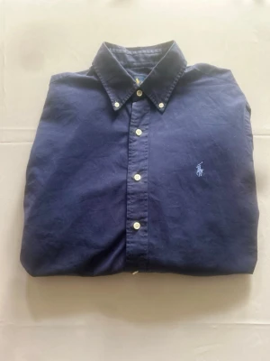 Ralph lauren skjorta - Klssisk Ralph Lauren skjorta i marinblå, storlek M. Skön bomullskvalitet med buttondown krage och broderad logga på bröstet. Mycket fint skick!
