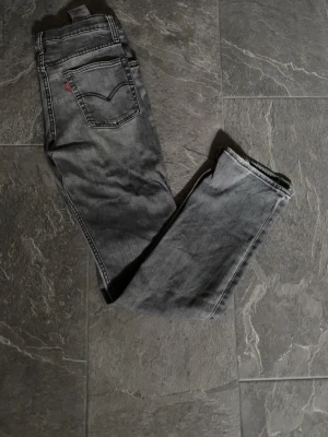 Grå Levi's raka jeans - Ett par gråa levis 501  med en tvättad grå look, väldigt stilrent och snyggt. Perfekta jeans i en jeansrotation. Jeansen är straight och sitter perfekt över skorna. Den beige levis lappen som sitter där bak har jag tagit bort då jag tycker det ser bättre ut utan. Annars är dom i väldigt bra skick, finns även möjligheter att göra slitningar på de om man vill det. Jag vet inte exakta storleken, men är 180 och de sitter rätt bra i längden på mig, lite möjligtvis pyttelite korta samt 31 Isch i midja