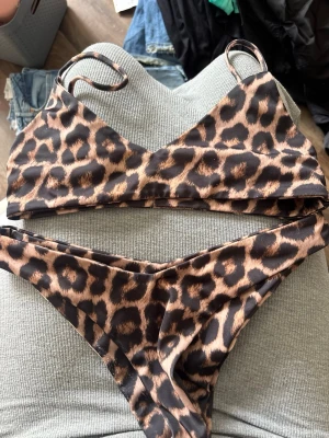 COCO&NUTS swim - Snygg bikini med leopardmönster i bruna och svarta toner. Överdelen har smala axelband och trekantsform, medan underdelen har en klassisk skärning. Perfekt för sommaren 