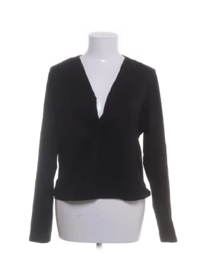 Svart långärmad v-ringad topp - En svart långärmad topp med v-ringning och enkel, stilren design. Toppen har en något figurnära passform och är perfekt för att skapa en clean och snygg look. Passar till många olika outfits och är ett måste i garderoben.