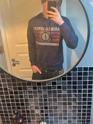 Mörkblå SL hoodie - Riktigt fet hoodie från Saint Laurent, passar perfekt till kyliga sommarkvällar, storlek S, helt nyskick med tagsen fortfarande på, jag har bara provat den aldrig haft den ute, säljer eftersom den inte passar min stil