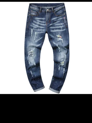 Blå slitna jeans med färgstänk - Helt ny beställde 2 st såg inte vill du ha mer information och bilder så skriv till mig bara. ett par blå jeans med coola slitningar, färgstänk och detaljerade sömmar. Jeansen har en avslappnad passform och uppvikta benslut. Perfekta för en trendig och avslappnad stil.