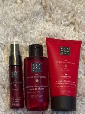 Rituals The Ritual of Ayurveda set - Set med tre produkter från Rituals The Ritual of Ayurveda: en röd sprayflaska, en duscholja och en whipped body cream. Alla produkter har en elegant röd design med svarta och silvriga detaljer. Innehåller doft av indisk ros och sötmandelolja.