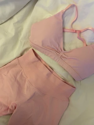 Rosa Prime crunche set från Relode - Säljer ett ljusrosa set från Relode med sport-bh och matchande höga shorts. Bh:n har smala axelband och lätt rynkning framtill, medan shortsen har bred midjeresår för extra komfort. Materialet är stretchigt och mjukt, perfekt för en aktiv vardag.