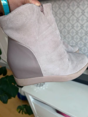 kilklackade stövletter - Snygga stövletter i  mocka . Skorna har kilklack och dragkedja på sidan för enkel påtagning. Perfekta för dig som vill ha både höjd och komfort i din look.