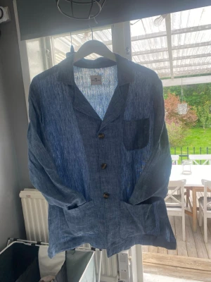 John Henric Overshirt i linne - Säljer en ljusblå overshirt från John Henric i ljusblå. Storleken är Small (Passar M). Skicket är mycket bra, inga defekter eller liknande! Materialet är i 100% linne och perfekt för varma dagar. Om du är intresserad, hör av dig!