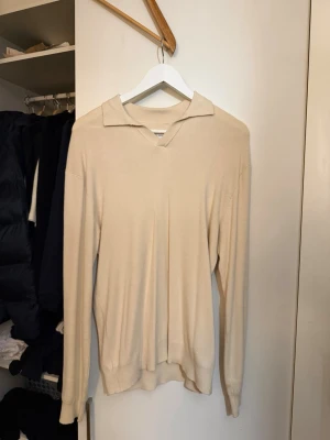 Selected home tröja - Snygg beige långärmad tröja med krage och v-ringning. Tröjan har en avslappnad passform och är tillverkad i ett mjukt material som känns skönt mot huden. Perfekt för dig som gillar stilrena och minimalistiska plagg.