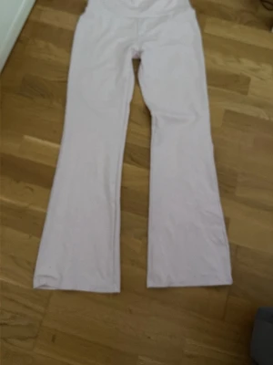 Ljusrosa bootcut leggings - Säljer ett par ljusrosa leggings med bootcut-modell. De har hög midja och är tillverkade i ett mjukt stretchigt material som sitter skönt på kroppen. Perfekta för dig som gillar en avslappnad men trendig stil.