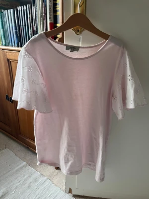 Ljusrosa topp med broderade ärmar - Supersöt ljusrosa topp från Samsøe Samsøe med vida, korta ärmar i broderad bomull med blommönster. Perfekt till jeans eller kjol för en fräsch look. Rund halsringning och mjukt material.