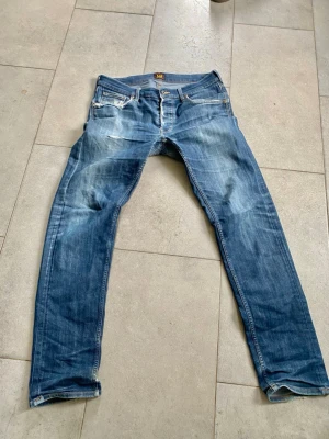 Blå slitna jeans från Lee - Säljer ett par riktigt snygga jeans från Lee med snygga fades och slitningar. Det finns defekter, se bilder. Storlek L32 W32