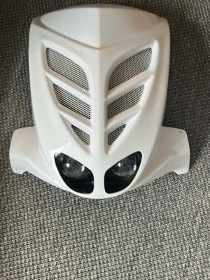 Vit bcd framkåpa till slider - Säljer en vit frontkåpa till moped med sportig design och inbyggda strålkastare. Kåpan har silverfärgade ventilationsgaller och är tillverkad i plast. Perfekt för dig som vill ge mopeden ett unikt utseende. Även helt sprillans ny.