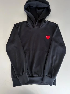 Comme Des Garçons Play Hoodie Herr - Svart hoodie från Comme des Garçons Play med klassisk huva och magficka. Nypris : ca 2000 SEK Pris : 499 SEK