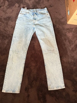 Ljusblå raka jeans från Levi's - Ljusblå jeans från Levi's med klassisk femficksdesign och raka ben. Jeansen har hög midja och är tillverkade i ett slitstarkt bomullstyg. Perfekta för en avslappnad och trendig look. Waist 25 och längd 30, 501 dam jeans 