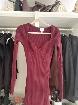 Vinröd ribbad långklänning H&M - Vinröd långklänning från H&M i ribbad trikå med markerad byst och lång ärm. 
