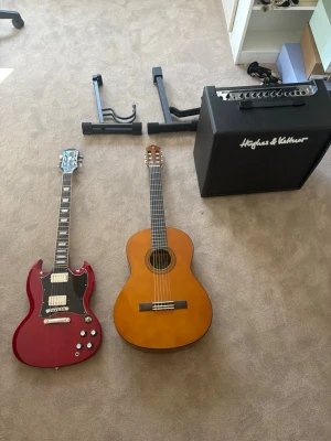 Elgitarr, klassisk gitarr & förstärkare - Säljer ett musikpaket med en röd elgitarr i SG-stil, en klassisk akustisk gitarr i träfärg samt en svart förstärkare från Hughes & Kettner. Perfekt för dig som vill spela både elgitarr och akustiskt. Gitarrställ och kablar ingår också. KOM MED BUD!